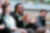 A woman with glasses speaks and gestures with her hands during a group discussion, while others listen attentively