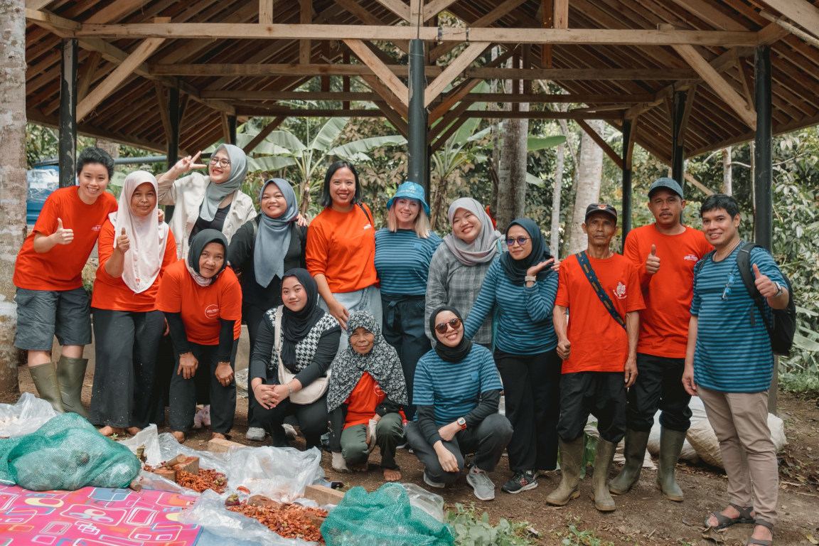 A group of IKEA co-workers and farm workers standing in front of an organic composting site on a mangosteen farm in Indonesia with social enterprise Java Fresh.