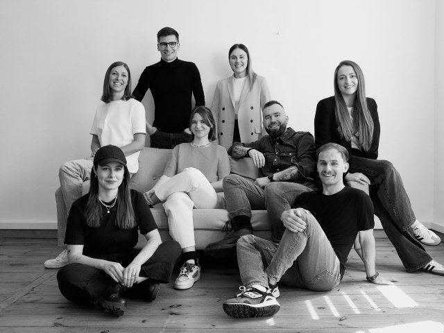 A black and white team photo of the eight person Dare Media team sitting and standing together.​